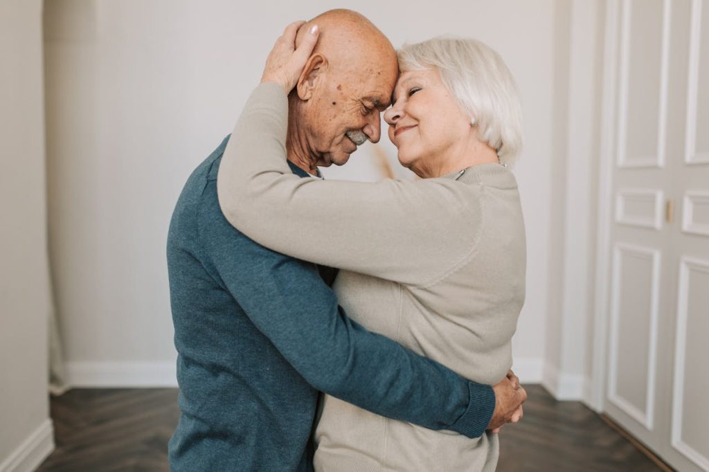 a-couple-hugging-each-other-5790829 A joyful elderly couple embracing indoors, expressing love and happiness.