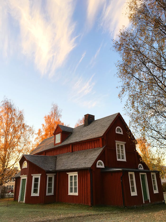 red-and-black-wooden-house-under-blue-sky-210538 Picturesque red wooden house in autumn. Traditional Swedish architecture amidst colorful foliage.